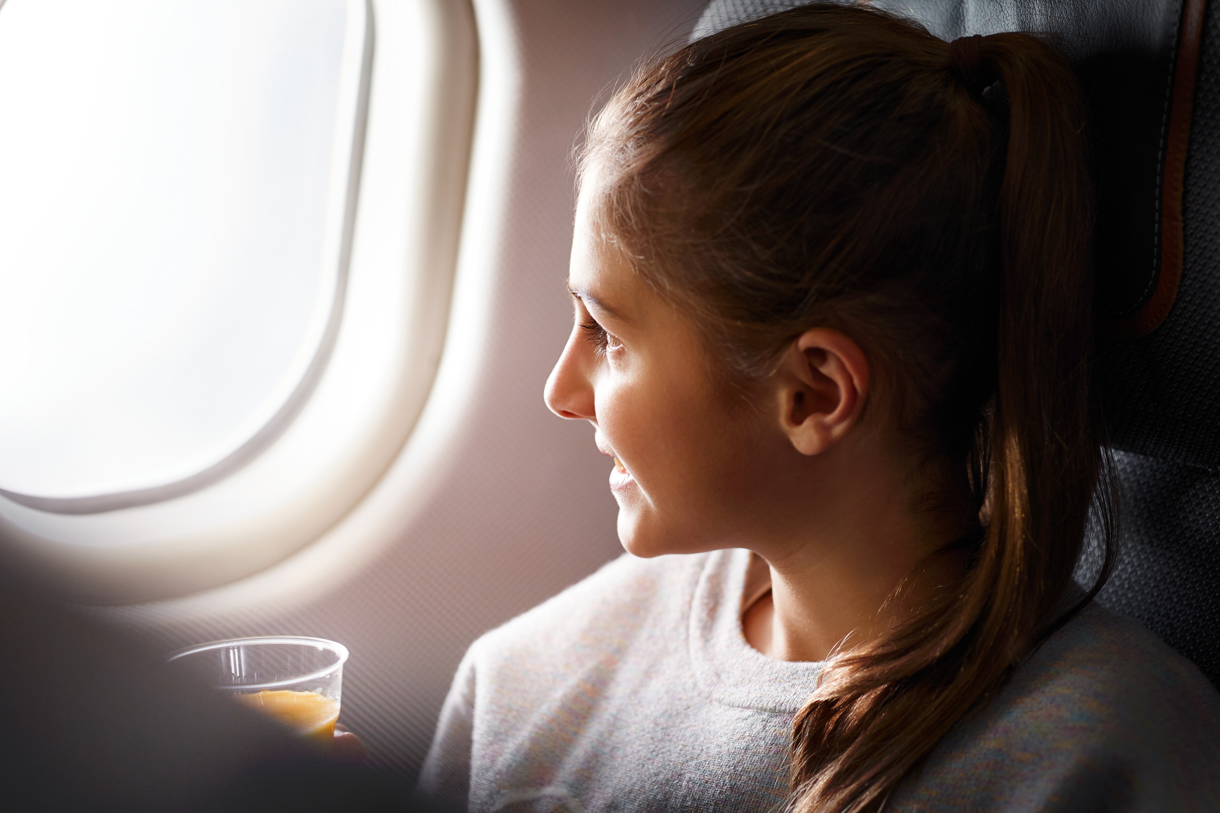 A child sits on a plane and looks outside