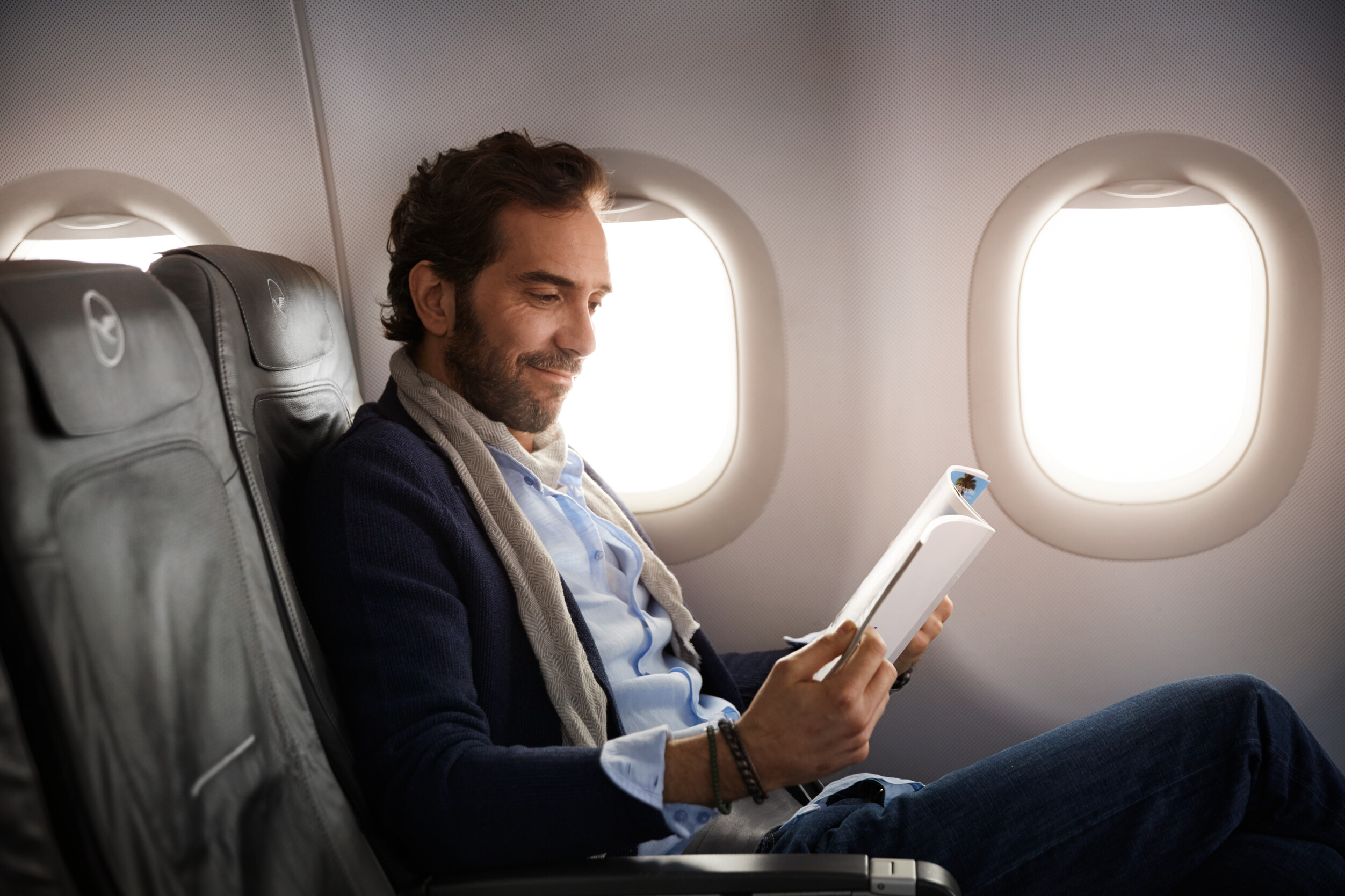 Passenger enjoying the flight in business class and reading a magazine